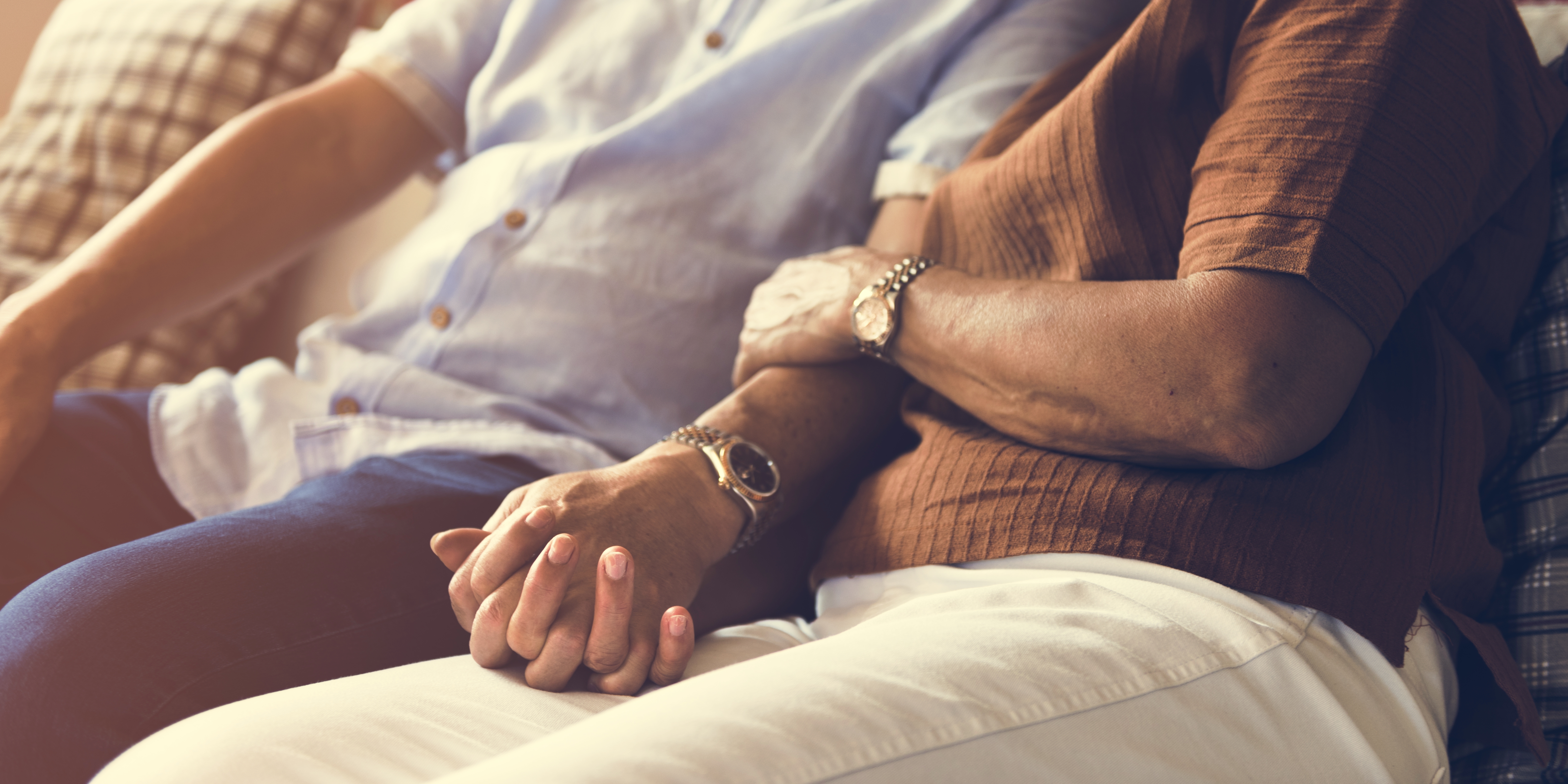 Una pareja cogida de la mano en el sofá de su casa